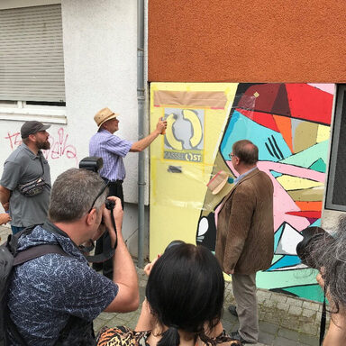 Stadtbaurat Nolda und Hr. Reißmann der Sozialgruppe Kassel e. V. sprayen das Logo Kassel Ost und stellen damit das Graffiti fertig