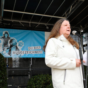 Eva Koch auf der Bühne vor einem Standmikrofon. Im Hintergrund das blaue Banner des Klimaschutzpreises