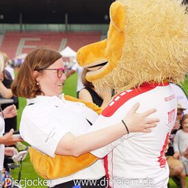 Eine Frau, die ein Löwenmaskottchen umarmt