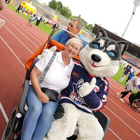 Ein Huskymaskottchen, das zusammen mit einer Frau auf einer Riksha sitzt