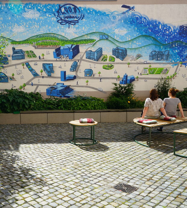Zwei Frauen sitzen im Innenhof des Stadtmuseums vor einem Graffiti.