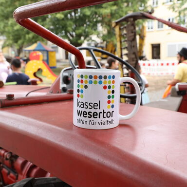 Eine Tasse mit der Aufschrift "Kassel Wesertor" steht auf einem Trecker