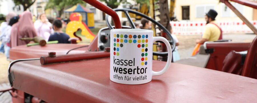 Tasse mit der Aufschrift Kassel Wesertor - offen für Vielfalt steht auf einem Trecker